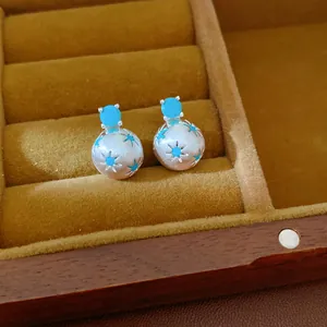 Dettaglio di eleganti orecchini in argento con pietre blu e sfere con motivo a stella.