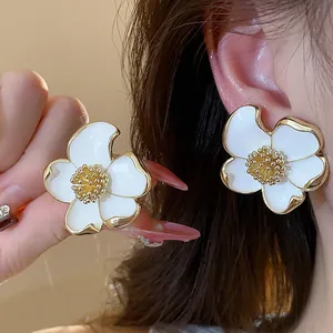 Détail en gros plan de boucles d'oreilles clip fleurs blanches en émail chic