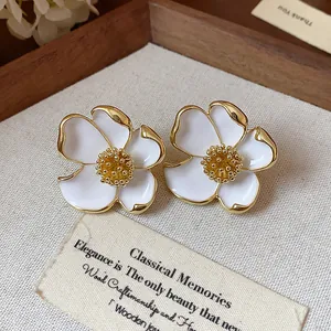 Gros plan détaillé sur des boucles d'oreilles fleurs en émail blanc avec pistils dorés
