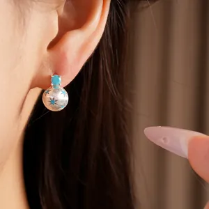 Primo piano di orecchini a sfera spazzolata color argento con pietre blu e stelle
