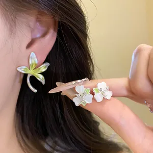 Detailed macro view of delicate white orchid flower stud earrings held on a fingertip