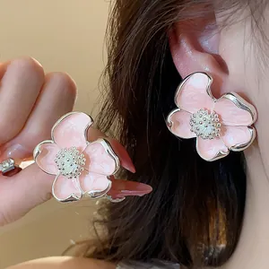 Gros plan de boucles d'oreilles à clip fleurs en émail rose avec bords argentés pour oreilles