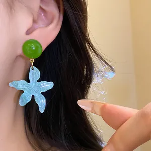 Detailed view of blue resin starfish dangle earrings being worn for summer beach vibes