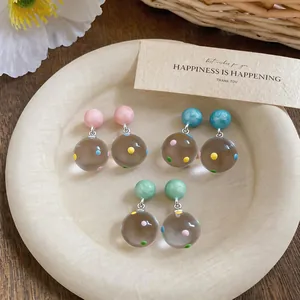 Detail view of clear resin polka dot earrings in pink, blue, and green variants.