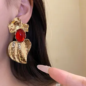 Statement gold hammered earrings with red resin stone in an exaggerated heart shape design
