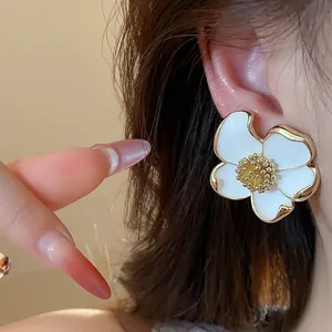 Gros plan d'une boucle d'oreille fleur blanche élégante avec des accents dorés.
