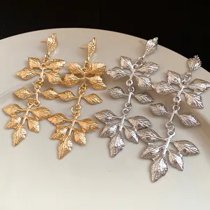 Gros plan détaillé des boucles d'oreilles feuilles froissées en finitions or et argent