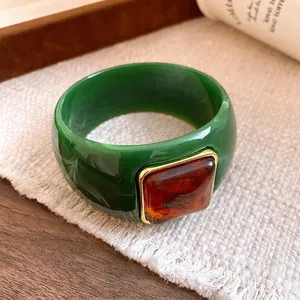 Elegant green acrylic bangle with a square faux-amber resin inlay and gold trim details.