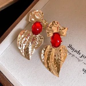 Exaggerated gold hammered heart earrings with red resin center