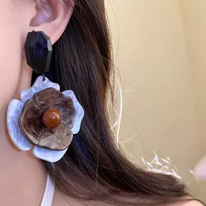 Detail shot of vintage acrylic flower pendant earrings with elegant brown and white finish
