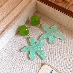 Detailed view of light blue resin starfish drop earrings with green studs.