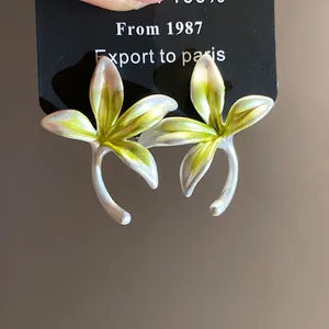 Detailed view of forest-style flower earrings with green and white gradient petals