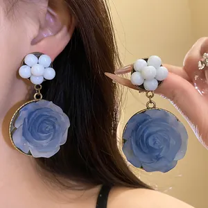 Close-up of blue resin rose earrings with white bead cluster accents