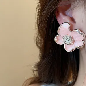 Gros plan d'un clip d'oreille fleur en émail rose avec un design floral délicat