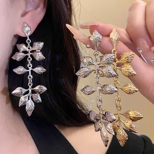Gros plan de boucles d'oreilles vintage en forme de feuilles dorées et argentées