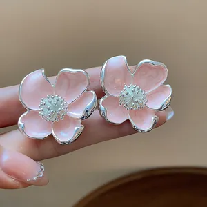 Gros plan d'élégants clips d'oreilles fleurs en émail rose avec détails argentés