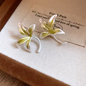 Close-up detail of delicate orchid flower earrings featuring green enamel and silver finish
