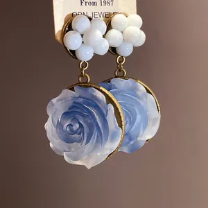 Detail of vintage blue resin rose earrings with white bead clusters and bronze finish