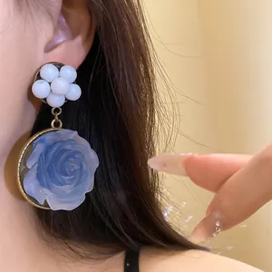 Close-up detail of blue resin rose earrings with white bead clusters in vintage style