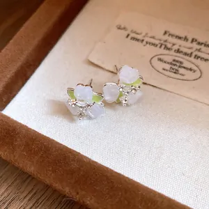 Detailed macro view of delicate forest-style flower earrings in a velvet jewelry box