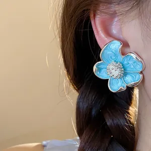 Détail élégant d'un clip d'oreille fleur en émail bleu clair pour femme sans perçage