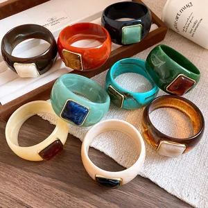 Collection of colorful acrylic bangles with square resin details in a stylish display