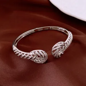 Elegant silver-tone twisted cuff bangle with sparkling zircon stones on brown fabric.