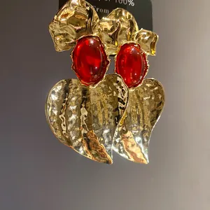 Detail view of gold hammered heart earrings featuring vibrant red oval resin centers