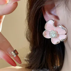 Détail d'un clip d'oreille fleur en émail rose avec des bords en argent poli