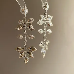 Vue détaillée des boucles d'oreilles pendantes feuilles en métal argenté texturé.