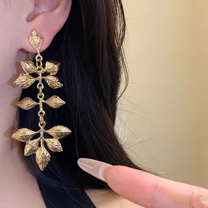 Détail haute qualité de boucles d'oreilles vintage en feuilles plissées dorées sur modèle