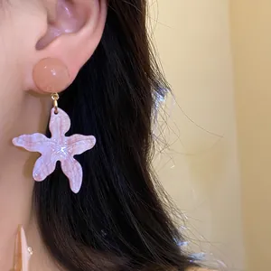 Detailed macro view of a lavender marbled starfish resin earring worn on an ear.