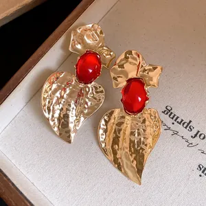 Macro view of vintage gold hammered heart earrings featuring bold red resin stone details