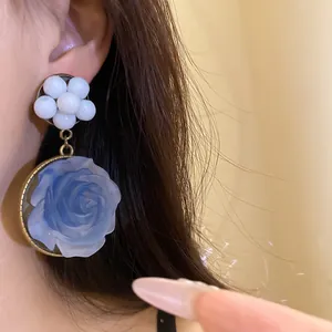 Close-up detail of blue resin 3D rose and white bead floral drop earrings in vintage style
