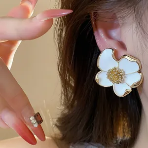 Vue détaillée d'un élégant clip d'oreille fleur en émail blanc avec des bords dorés
