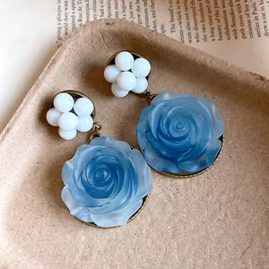 Detailed macro view of vintage blue resin rose earrings with delicate white bead clusters