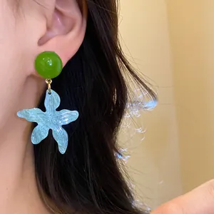 Detailed view of summer beach style resin starfish dangle earrings worn by a model