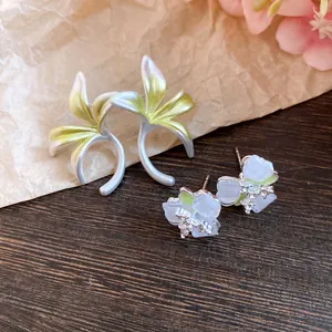 Close-up of delicate forest-style flower earrings with enamel and crystal details