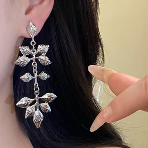 Détail de boucles d'oreilles à pampilles en feuille d'argent sur un mannequin asiatique.