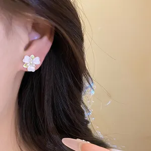 Close-up of elegant white orchid flower stud earring worn by model with soft lighting