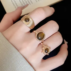 Dettaglio di un set di tre anelli aperti vintage in resina dorata indossati sulla mano
