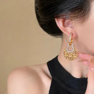 Detailed view of 18K gold-plated earrings with cubic zirconia and hollow gourd design.