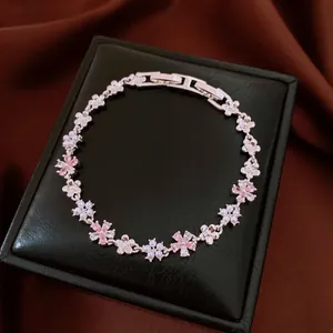 Close-up of elegant floral bracelet with pink zircons and pearls on black gift box.