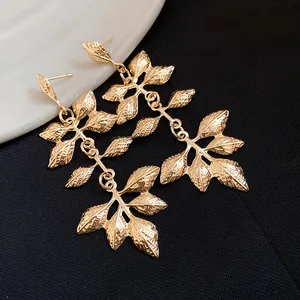 Vue macro détaillée des boucles d'oreilles pendantes feuilles en métal doré plissé