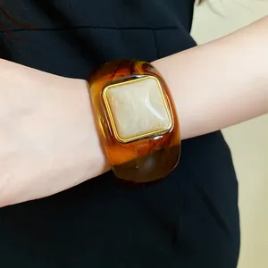 Close-up detail of a vintage amber acrylic bangle featuring a square marble inlay