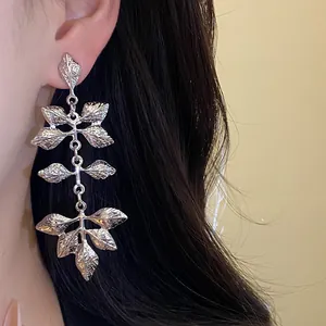 Vue rapprochée d'élégantes boucles d'oreilles pendantes en forme de feuille argentée.