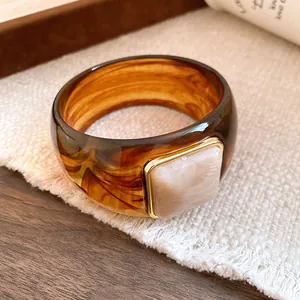 Close-up of a tortoiseshell acrylic bangle with a square marble-style centerpiece