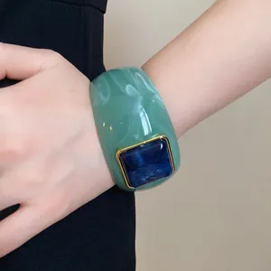 Detailed shot of green marble acrylic bangle with dark blue square insert on model wrist