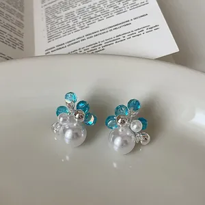 Close-up of elegant flower earrings with blue crystals and white pearls in a tray.