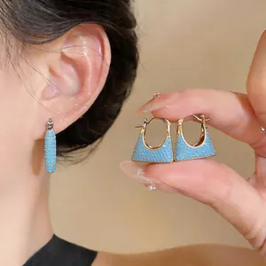 Detaillierte Ansicht eleganter 18 Karat vergoldeter Trapez-Creolen mit blauen Steinen